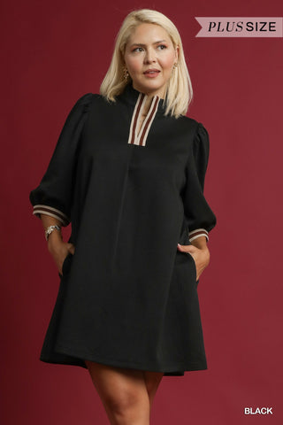 Woman wearing a black dress with long sleeves against a red background