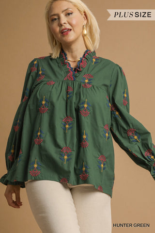 Woman wearing a green embroidered blouse with a beige background