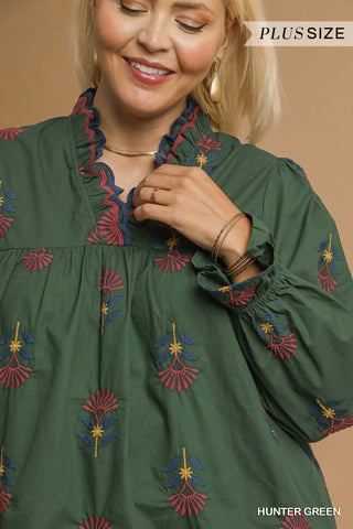 Woman wearing a green dress with colorful embroidery, labeled 'Plus Size' and 'Hunter Green'.