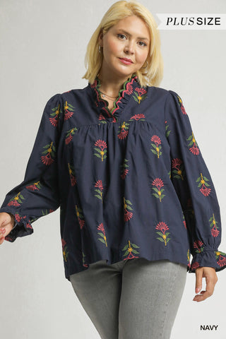 Woman wearing a navy blouse with floral patterns on a plain background