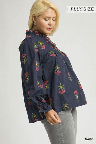 Woman wearing a navy blue blouse with floral embroidery on a white background