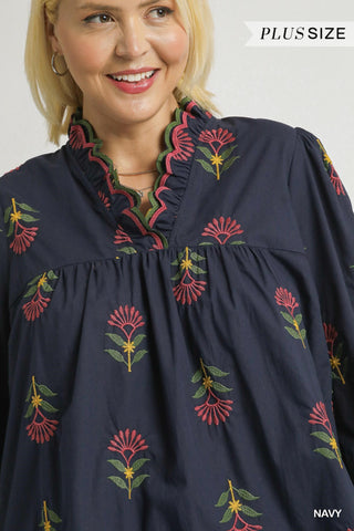 Woman wearing a navy blue blouse with floral embroidery, labeled 'Plus Size'.