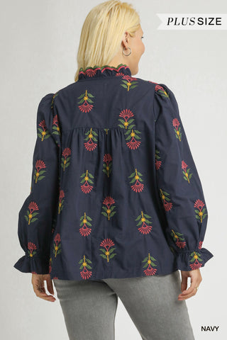 Navy blouse with floral embroidery worn by a model on a plain background