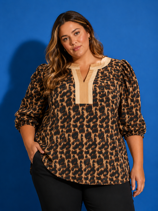 Woman wearing a leopard print blouse with a beige collar against a blue background