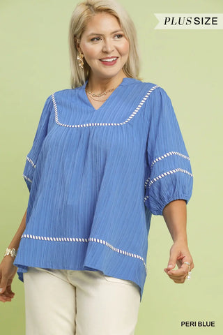 Woman wearing a blue blouse with white trim against a light green background