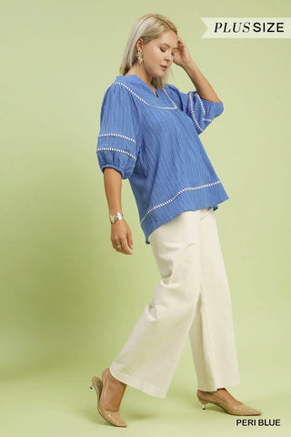 Woman wearing a blue blouse and white pants on a light green background