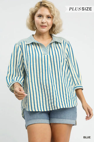 Woman wearing a blue and white striped shirt with denim shorts on a gray background