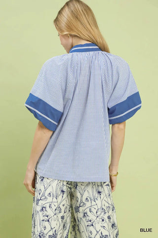 Person wearing a blue and white striped shirt with floral pants on a light green background