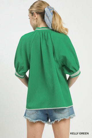 Woman wearing a green blouse with white trim on a white background
