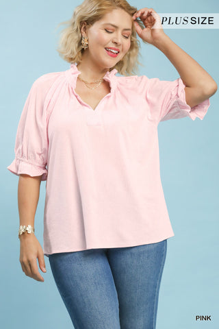 Woman wearing a pink blouse and blue jeans on a light blue background