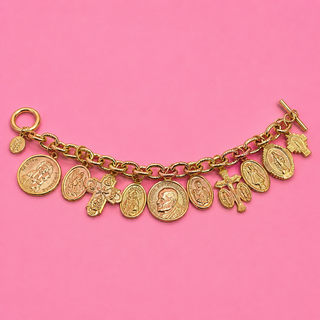 Gold charm bracelet with various charms on a pink background