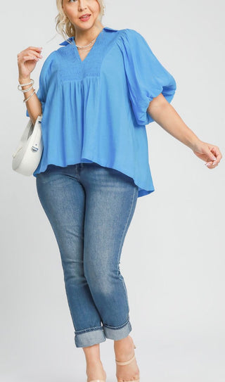 Woman wearing a blue top and jeans on a plain background