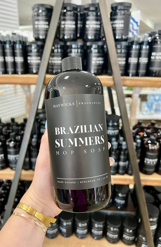 Person holding a bottle of 'Brazilian Summers' soap with shelves of similar products in the background.