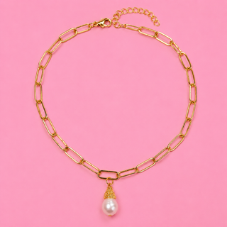Gold chain necklace with a pearl pendant on a pink background