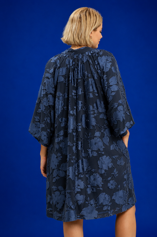 Woman wearing a dark floral dress against a blue background
