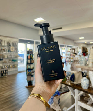 Hand holding a bottle of Orleans Luxury Foaming Hand Wash in a store setting