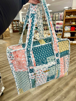 Patchwork patterned bag held by a person in a store setting