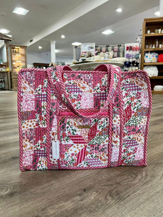 Pink patchwork tote bag on a wooden floor in a store setting