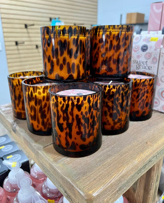 Leopard print candles on a wooden shelf with a blurred background