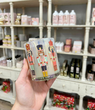 Hand holding a glass with nutcracker design in a store setting