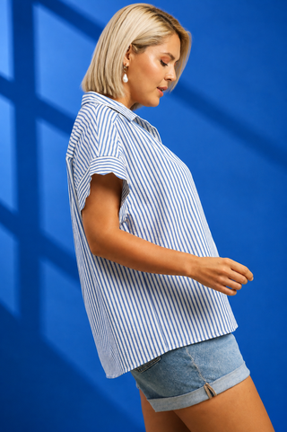 A woman modeling a short-sleeve button-up shirt with vertical blue and white stripes