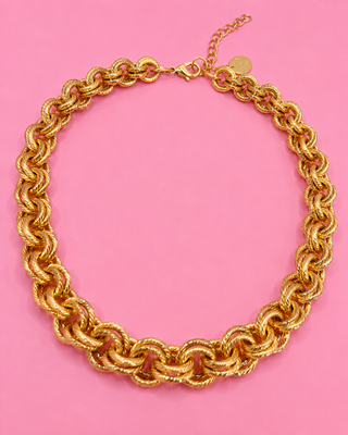 Gold chain necklace on a pink background