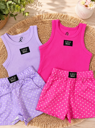 The set includes a light lavender top and shorts with white polka dots, a bright pink top with white polka dots, and a laven