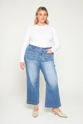 Woman wearing a white top and blue jeans on a white background