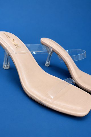 A pair of beige heeled slide sandals with clear transparent straps