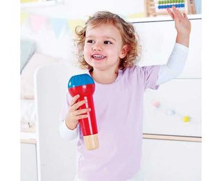 Child holding a colorful toy microphone in a bright room