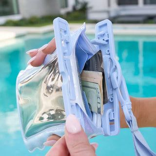 Hand holding a transparent pouch with money and cards by a pool