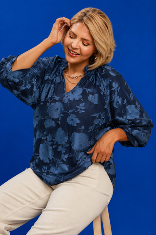 Woman wearing a blue floral blouse against a blue background