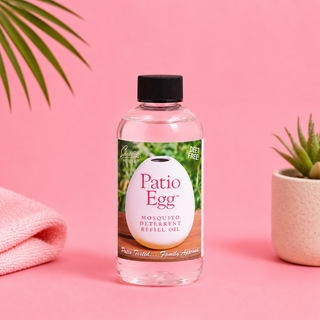 Bottle of Patio Egg mosquito deterrent refill oil on a pink background with a plant and towel.