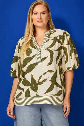 Woman wearing a leaf-patterned blouse against a blue background