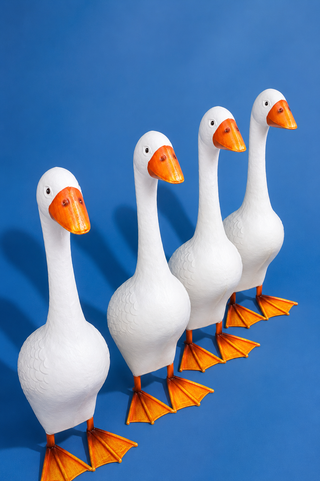 Four white goose figurines with orange beaks and feet on a blue background