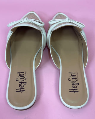 Pair of white shoes with bows on a pink background