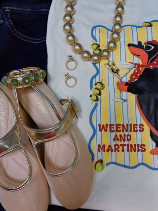 A woman modeling a cream-colored graphic t-shirt with a vintage-style weenie dog print "weenies & martinis