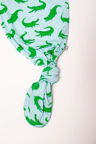 Light blue headscarf with green alligator patterns on a light pink background