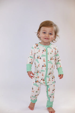 Child wearing a patterned onesie with green trim on a white background