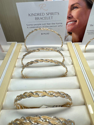 Gold bracelets in a display case with 'Kindred Spirits' bracelet card.