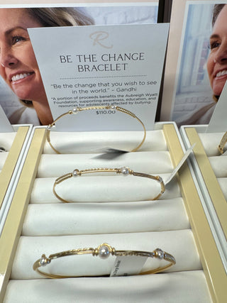 Gold bracelets on display with a card behind them