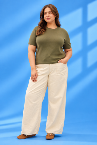 A woman modeling a short-sleeve olive green t-shirt and wide-leg cream pants