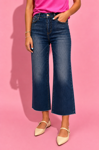Person wearing blue jeans and a pink top on a pink background