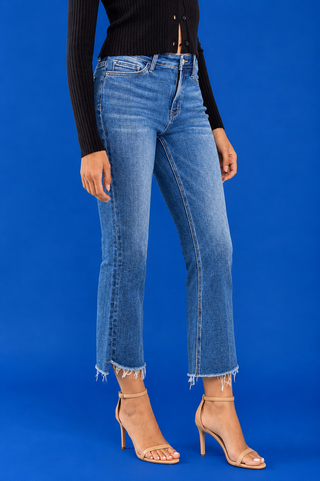 A model wearing medium-wash blue cropped flare jeans with a raw frayed hem