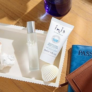 Cosmetic products including a bottle and tube labeled 'inis' on a wooden surface with a passport and shell.