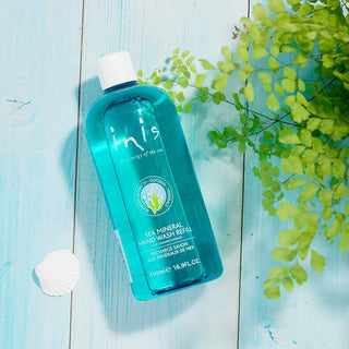 Blue hand wash bottle with green leaves on a light blue wooden surface