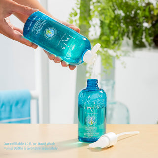 Hand holding a blue bottle with a pump, next to another blue bottle on a table outdoors.