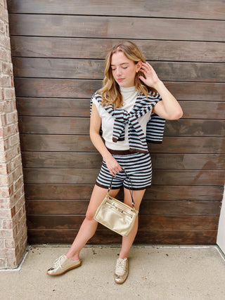 A young woman modeling a matching black and white striped long-sleeve top and shorts set with a dark brown trim