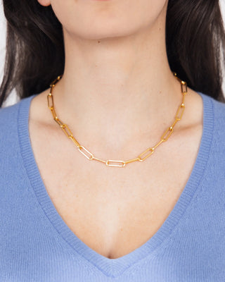 Gold chain necklace worn by a person with a blue shirt