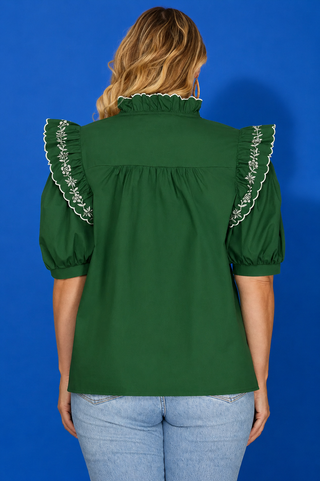 Green puff-sleeve blouse with light-wash jeans.